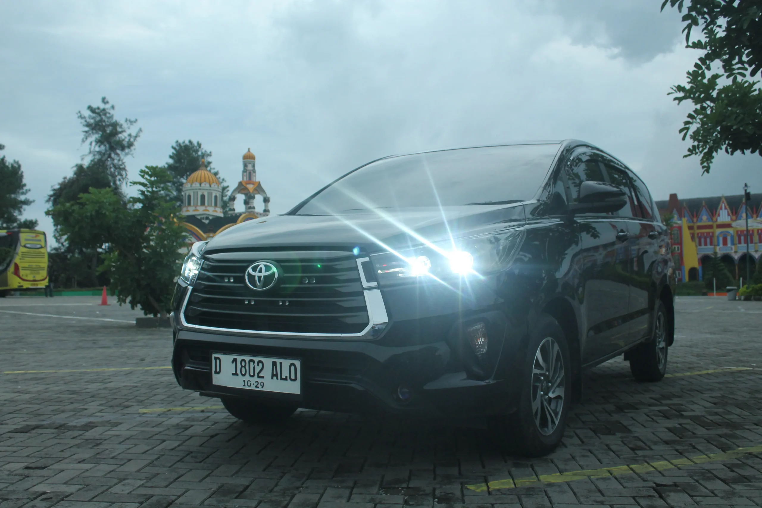 Innova Reborn hitam parkir di area wisata Bandung siap disewa untuk keluarga.