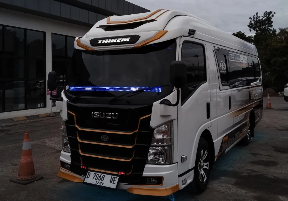 Elf Long putih parkir di area wisata Curug Cinulang siap mengangkut rombongan. Rental Elf Wisata Bandung Timur